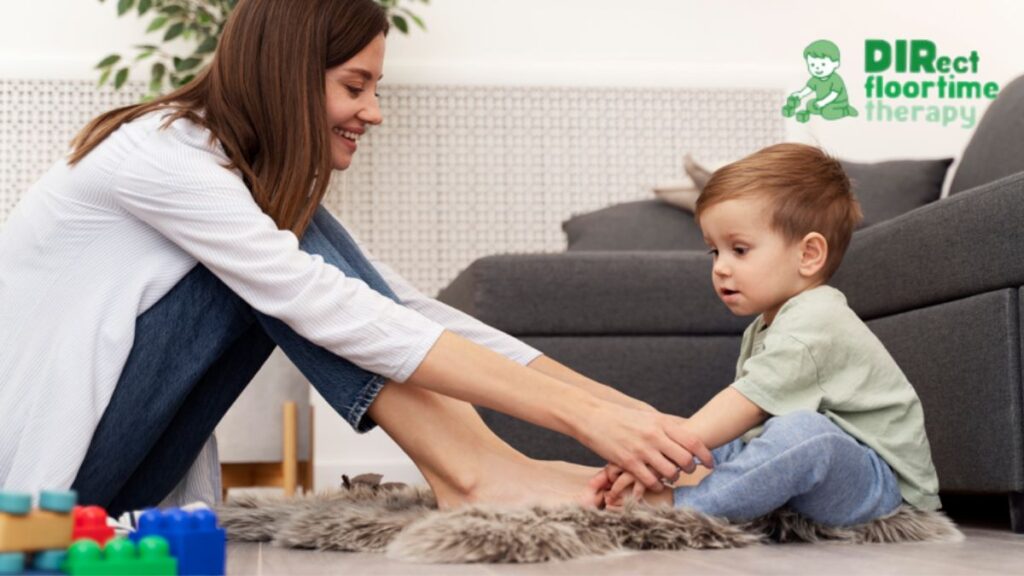 A female therapist guides a young child to play with toys during a DIR/Floortime session.