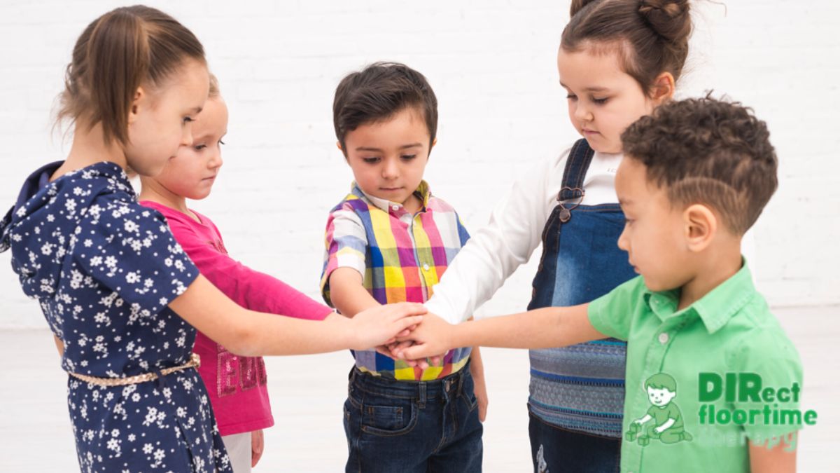 Social skills counseling session where a group of children place their hands together in a circle before starting a game.