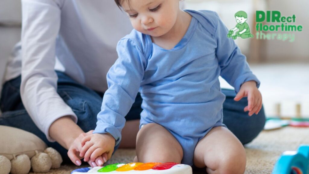 A 6-month-old explores a xylophone, guided by an adult, concentrating with a focused, serious expression.