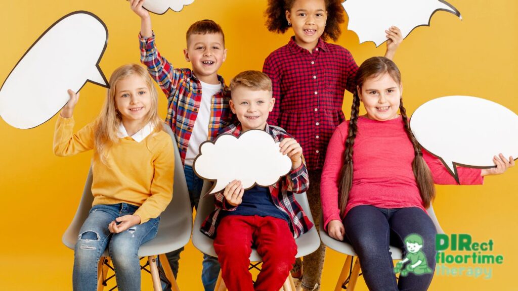 Students in an autism classroom share a joyful moment, posing for the camera while holding talk bubble cards during a DIR Floortime activity.