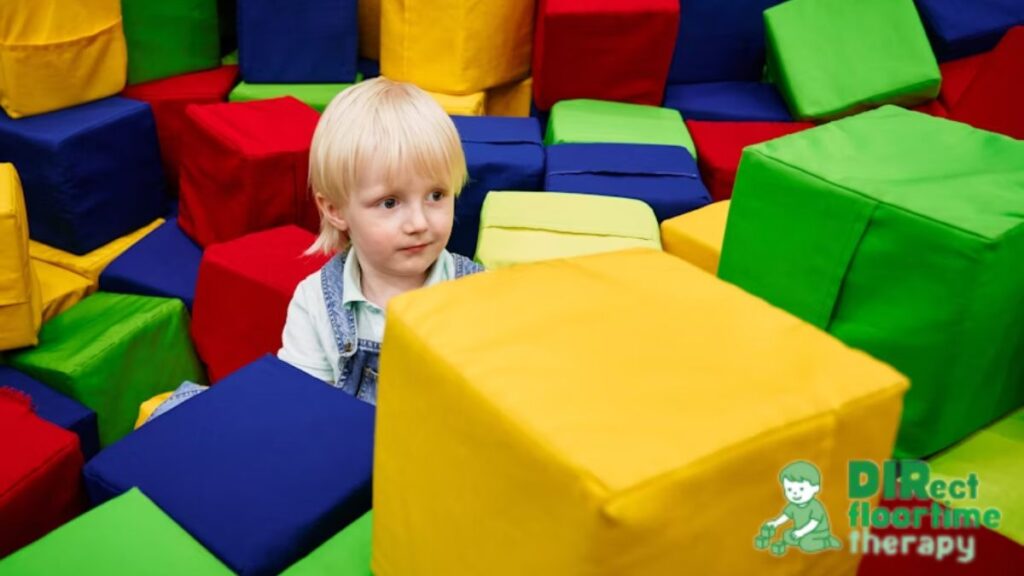 A young boy with autism explores a space filled with large soft cubes, encouraging physical activity and curiosity as part of a sensory diet example.