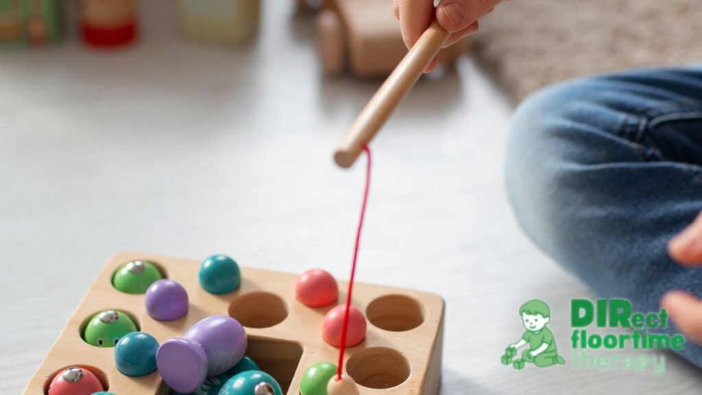 Sensory diet autism example, a child engages in a simulated fishing game using strings and wooden balls on a platform to build focus and coordination.