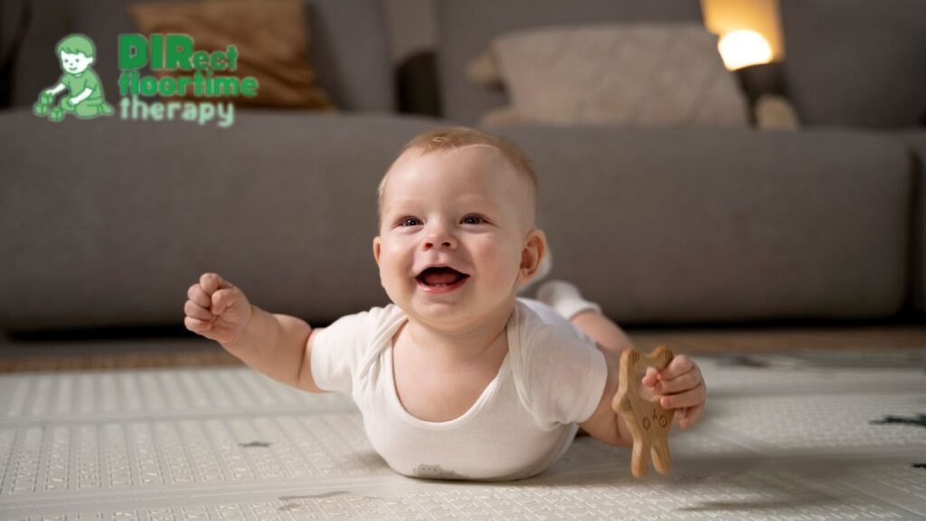 A baby in a onesie smiles joyfully while doing tummy time on a white rug, moving in a playful, swim-like motion.