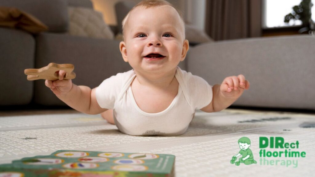 A baby in a white onesie does tummy time on the floor, smiling gleefully at the camera as the central focus.