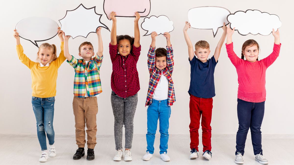 A group of children pose joyfully against a white background, holding up colorful speech bubbles to represent communication during a DIR Floortime speech therapy session.