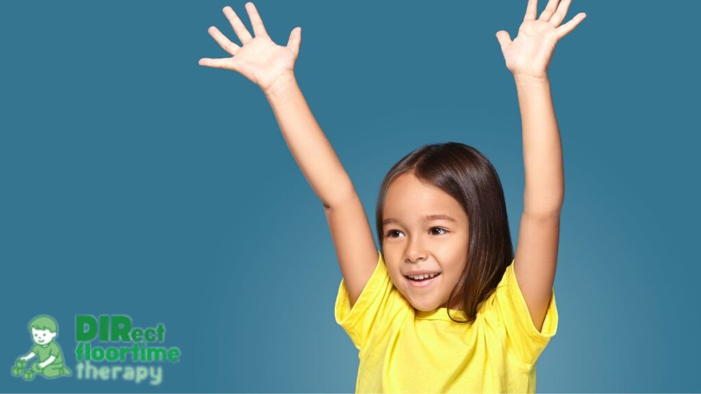 A young girl smiles and raises her hands above her head while swaying.