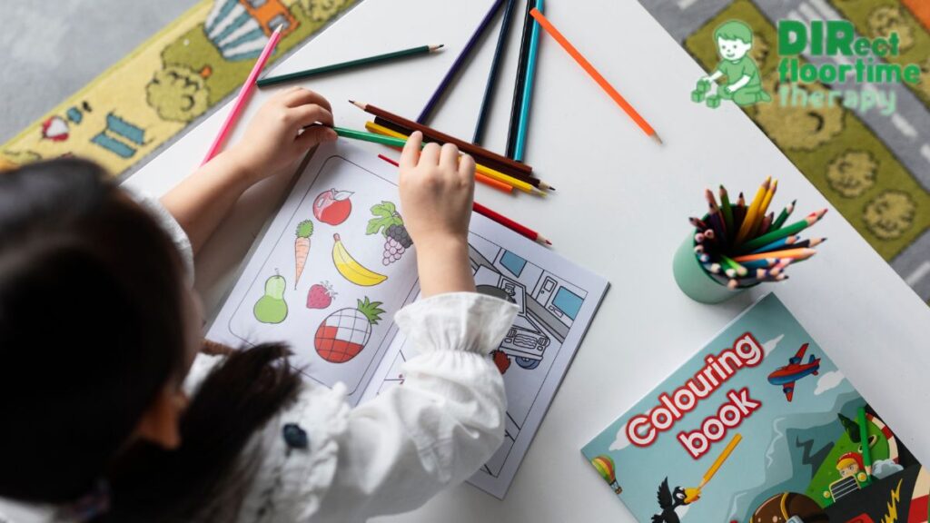 Top view of a girl working on a coloring book with art materials scattered across the table.