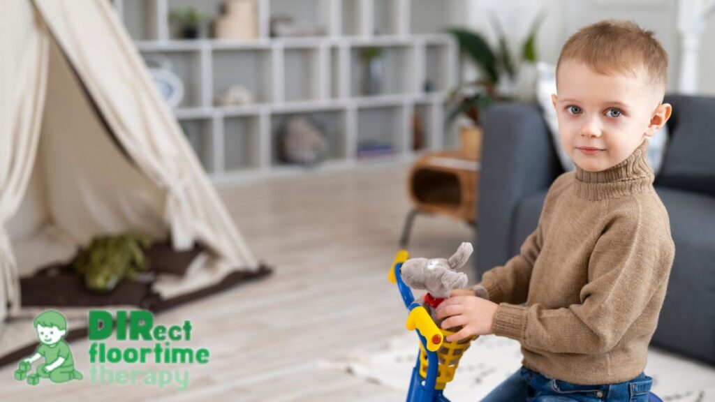 School readiness autism, a toddler-age boy looking confidently at the camera amid a playroom activity.