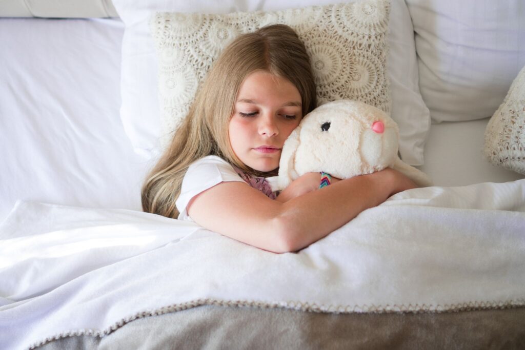 Why Autistic Girls Are Diagnosed Later and What NJ Parents Need to Know About the Female Autism Profile 1 A girl lying on her bed experiencing autism-related after-school exhaustion, looking calm with stuffed animals around her in a peaceful private space.