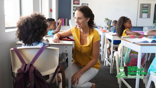 A teacher kneeling at a child's level in a classroom, both smiling, the child appearing relaxed and engaged
