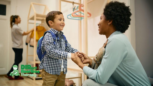 A teacher kneeling at a child's level in a classroom, both smiling, the child appearing relaxed and engaged