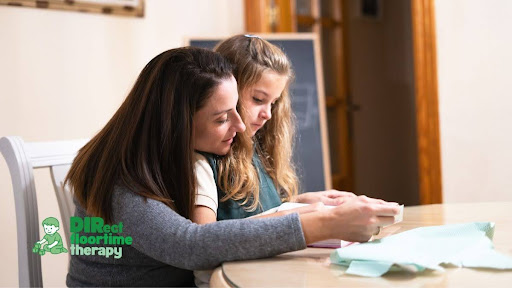 A parent and child sitting together at a kitchen table, looking at a simple visual schedule or calendar, both calm and engaged